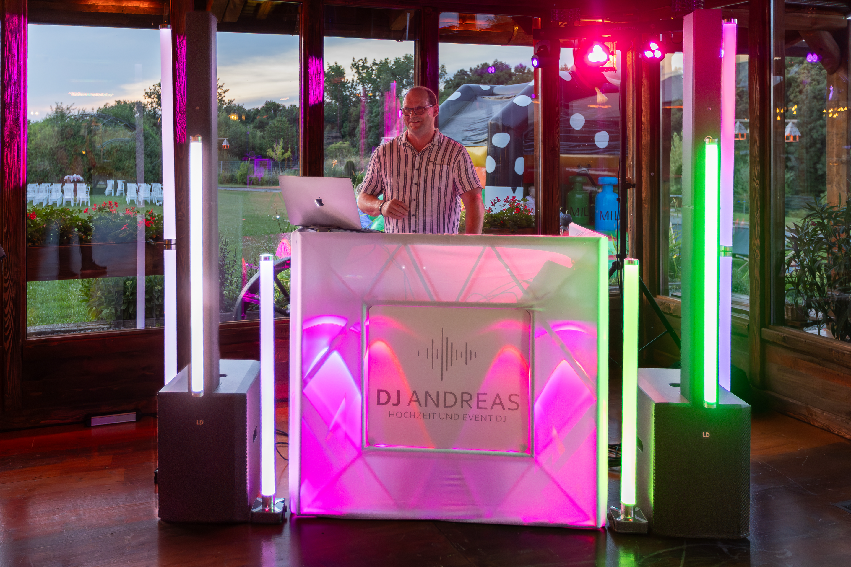 DJ Andreas bei einer Freien Trauung – professionelles DJ-Pult mit Lichttechnik und Laptop, stimmungsvolle Beleuchtung in einer Location mit Blick ins Grüne.